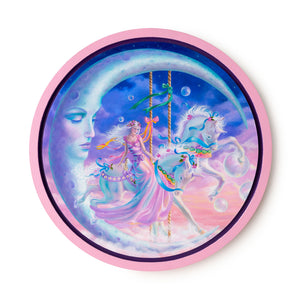 Round oil painting in in pink wooden frame with pinks and blues of a woman in a pink long gown on a white carousel horse with blue ribbons against a backdrop of pink and blue clouds under a large crescent moon with an austere downcast expression.