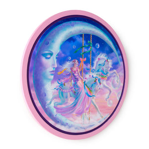 Side view of a round oil painting in frame withpinks and blues of a woman in a pink long gown on a white carousel horse with blue ribbons against a backdrop of pink and blue clouds under a large crescent moon with an austere downcast expression.